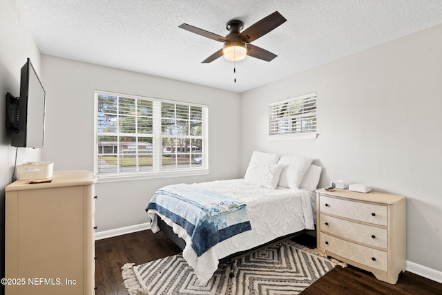 bedroom featuring a ceiling fan, a textured ceiling, baseboards, and wood finished floors