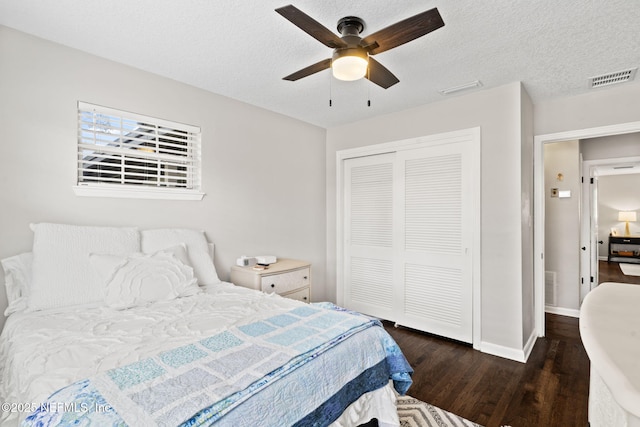 bedroom featuring baseboards, visible vents, wood finished floors, a textured ceiling, and a closet