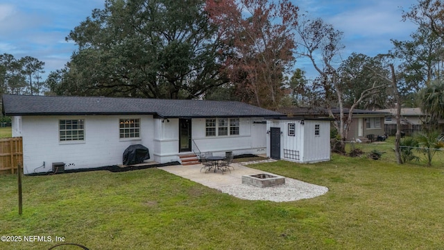 rear view of property featuring entry steps, a patio, a fire pit, fence, and a yard