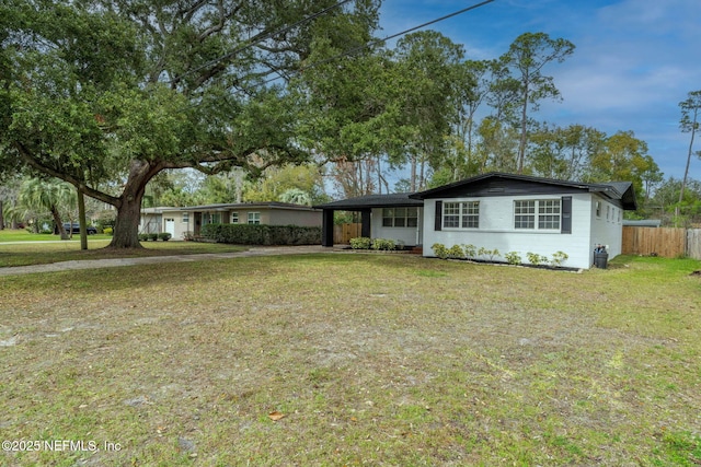 single story home with a carport, a front yard, concrete block siding, and fence