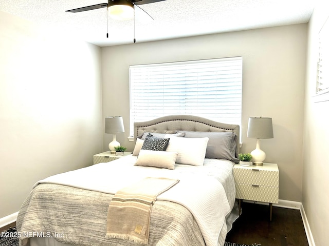 bedroom featuring baseboards, wood finished floors, ceiling fan, and a textured ceiling