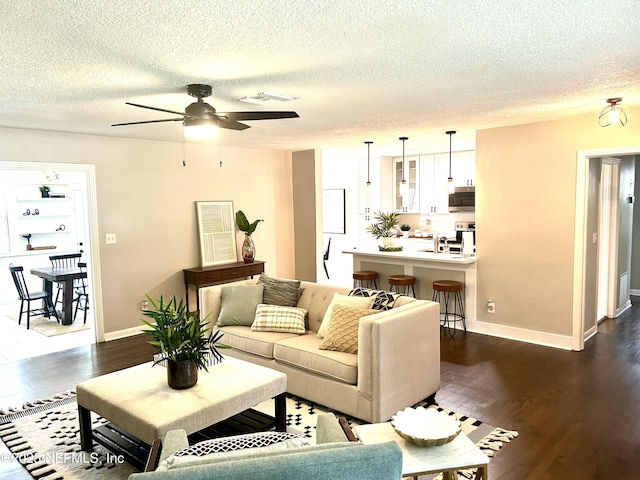 living room featuring visible vents, ceiling fan, a textured ceiling, and dark wood finished floors
