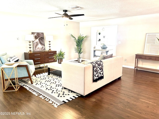 living room featuring a ceiling fan, visible vents, wood finished floors, and baseboards