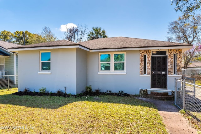 view of front of property featuring a front lawn, a shingled roof, fence, and stucco siding