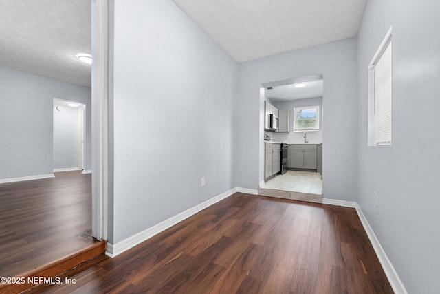 corridor featuring light wood finished floors, a sink, and baseboards