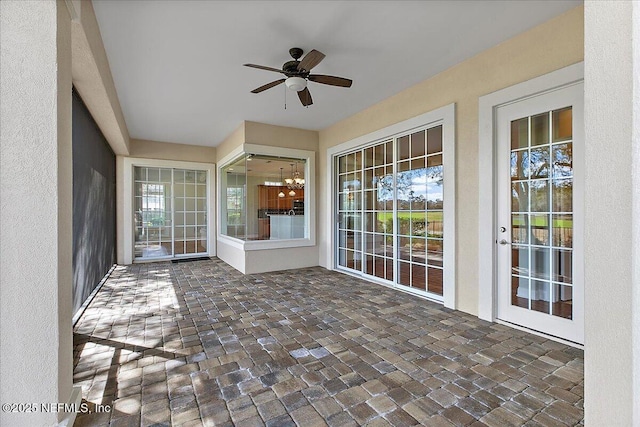 unfurnished sunroom with ceiling fan with notable chandelier and plenty of natural light