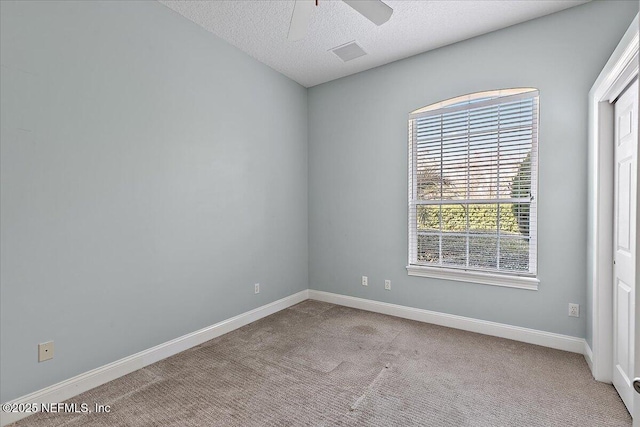 spare room with visible vents, light carpet, ceiling fan, a textured ceiling, and baseboards