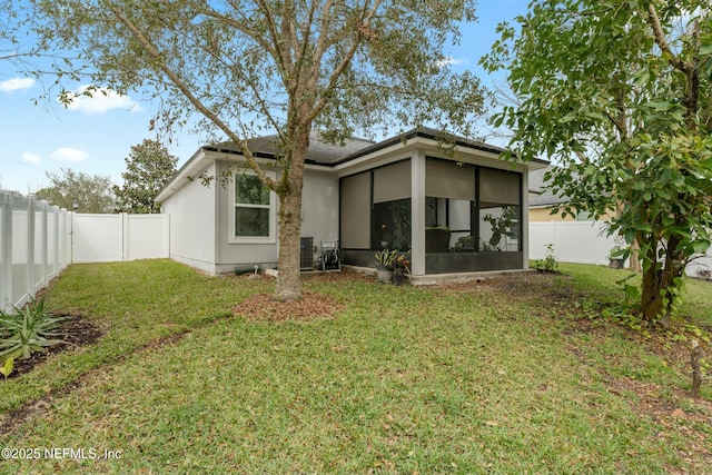 back of property with a yard, a fenced backyard, and a sunroom