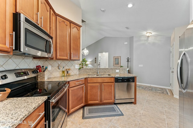 kitchen featuring stainless steel appliances, brown cabinets, a sink, and a peninsula