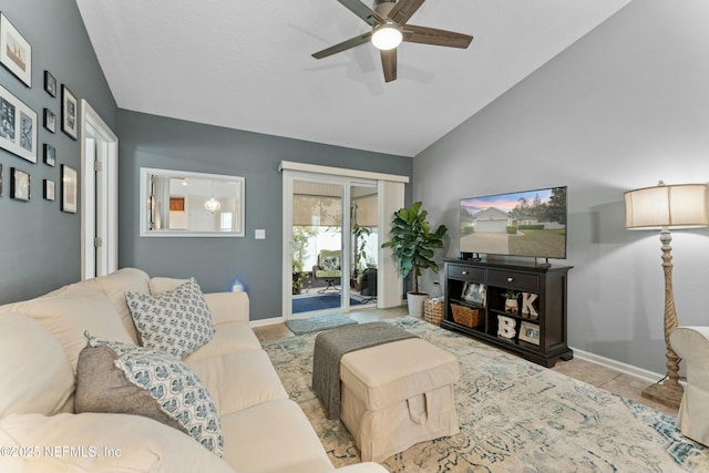 living area featuring lofted ceiling, tile patterned floors, a ceiling fan, and baseboards