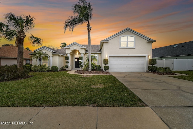 view of front of home with a yard, stucco siding, concrete driveway, fence, and a garage