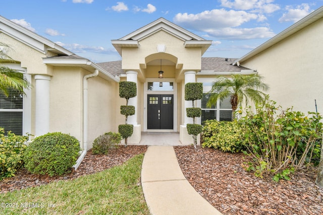 property entrance featuring roof with shingles and stucco siding