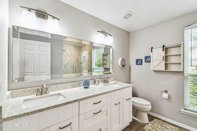 full bathroom with a marble finish shower, visible vents, a sink, and toilet