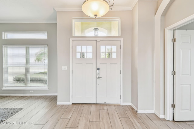 entrance foyer featuring baseboards, ornamental molding, plenty of natural light, and wood tiled floor