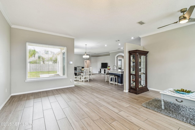 interior space with light wood-style floors, visible vents, crown molding, and baseboards