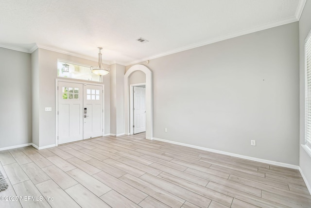 entryway featuring visible vents, arched walkways, baseboards, light wood-style flooring, and crown molding