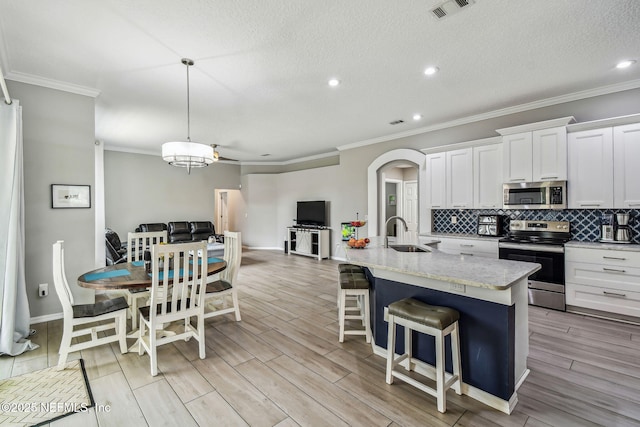 kitchen with visible vents, arched walkways, decorative backsplash, appliances with stainless steel finishes, and a sink