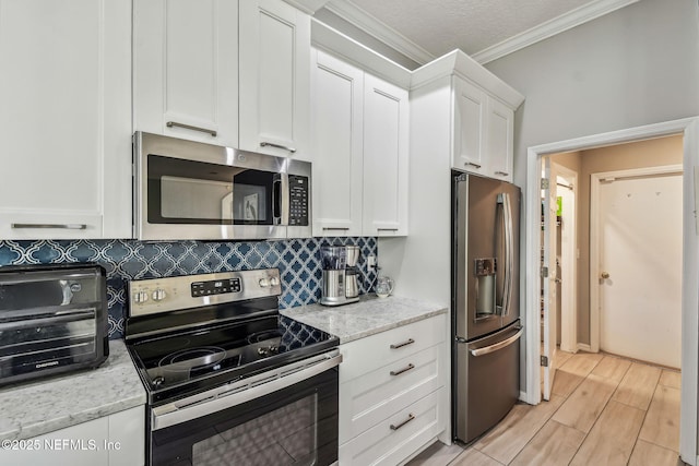 kitchen featuring backsplash, appliances with stainless steel finishes, light wood-style floors, ornamental molding, and white cabinetry