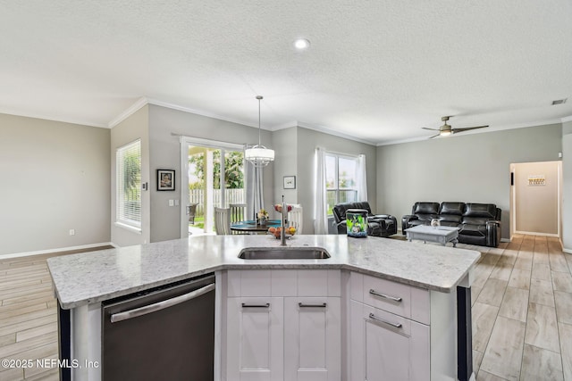 kitchen featuring light wood finished floors, stainless steel dishwasher, open floor plan, a sink, and light stone countertops