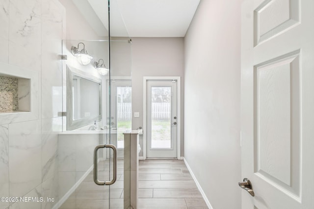 bathroom featuring a shower stall and baseboards