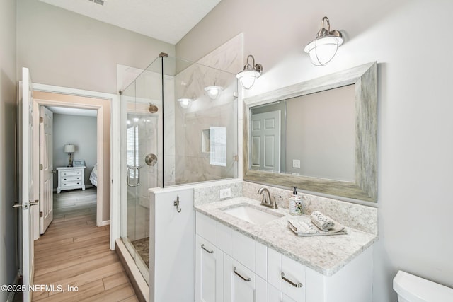 full bathroom featuring a shower stall, wood finished floors, connected bathroom, and vanity