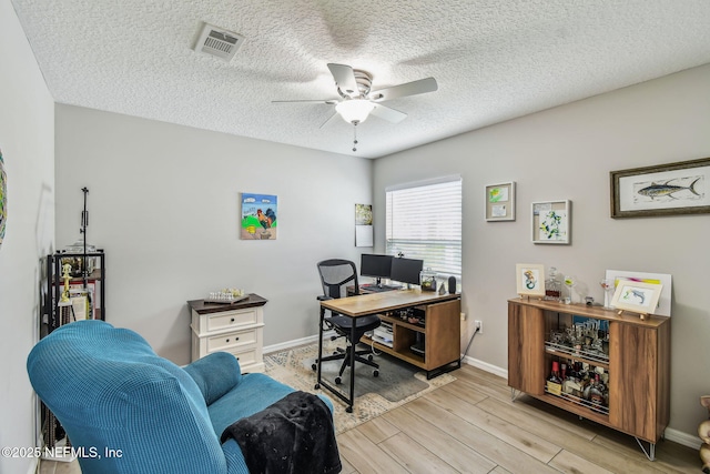 office with ceiling fan, a textured ceiling, wood finished floors, visible vents, and baseboards