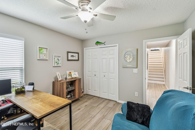 office space featuring light wood-style flooring, a ceiling fan, and a textured ceiling