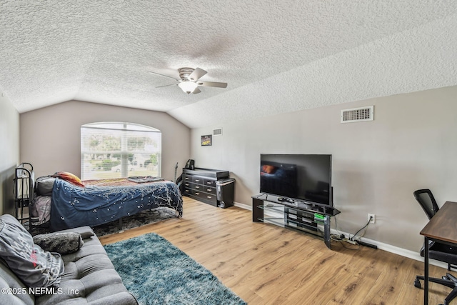 bedroom featuring vaulted ceiling, a textured ceiling, wood finished floors, and visible vents