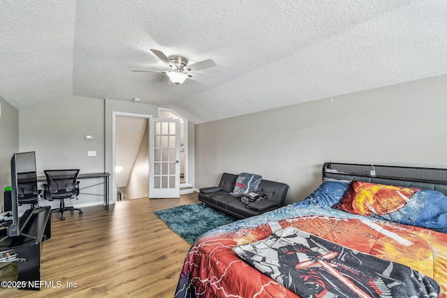 bedroom with a ceiling fan, lofted ceiling, a textured ceiling, and wood finished floors