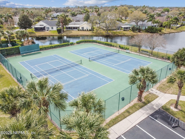 view of sport court featuring a residential view, a water view, and fence