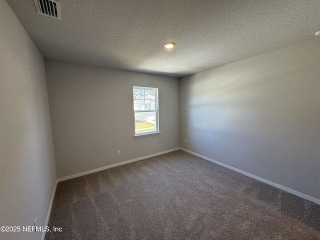 empty room with a textured ceiling, carpet flooring, visible vents, and baseboards