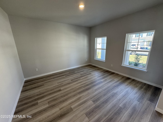 unfurnished room featuring baseboards and dark wood-type flooring