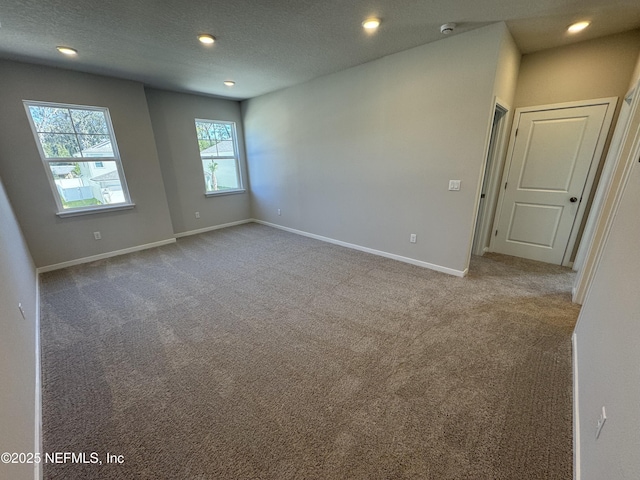 unfurnished room with carpet, baseboards, a textured ceiling, and recessed lighting