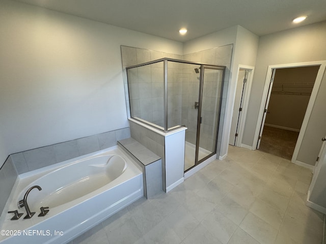 full bath featuring a stall shower, baseboards, a walk in closet, a bath, and recessed lighting