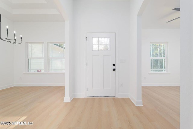 foyer with light wood finished floors, baseboards, and arched walkways