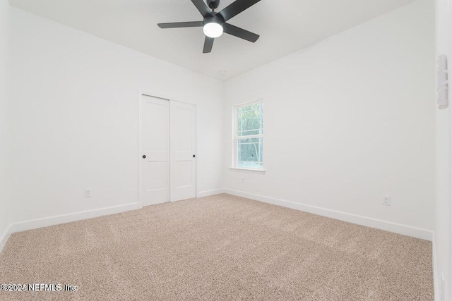 unfurnished bedroom featuring carpet, a closet, ceiling fan, and baseboards