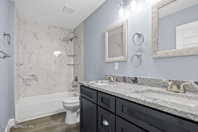 bathroom featuring toilet, a textured ceiling, a sink, and wood finished floors