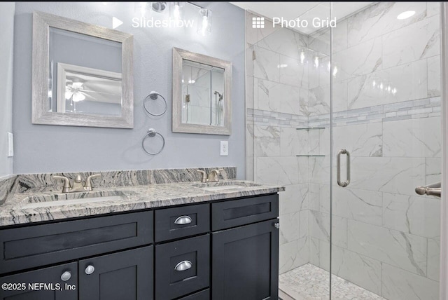 full bathroom featuring a sink, a marble finish shower, and double vanity