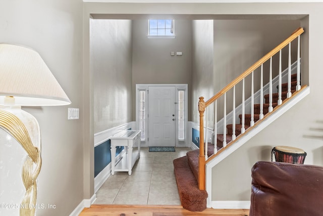 entryway featuring stairway, tile patterned flooring, a towering ceiling, and baseboards