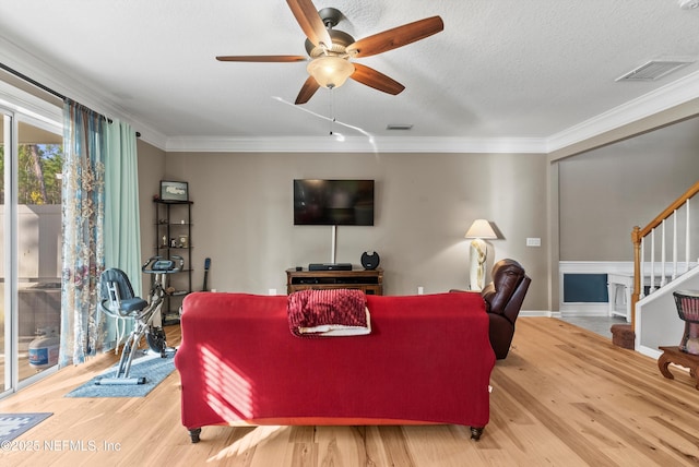 living room with ornamental molding, wood finished floors, visible vents, and stairs