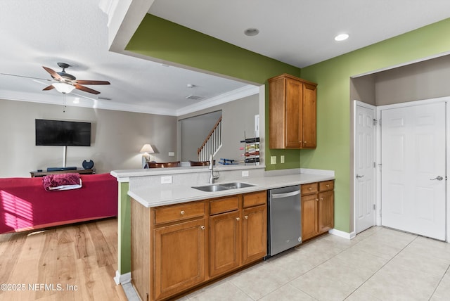 kitchen featuring brown cabinetry, light countertops, a sink, and stainless steel dishwasher