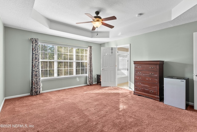 unfurnished bedroom featuring a tray ceiling, refrigerator, a textured ceiling, and baseboards