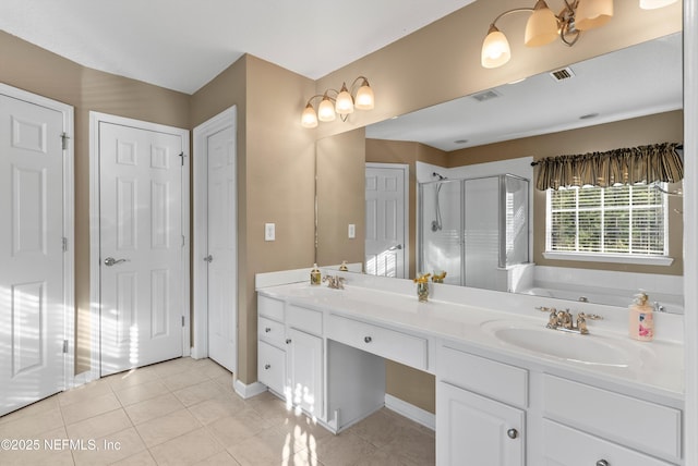 bathroom featuring double vanity, a stall shower, a sink, and tile patterned floors