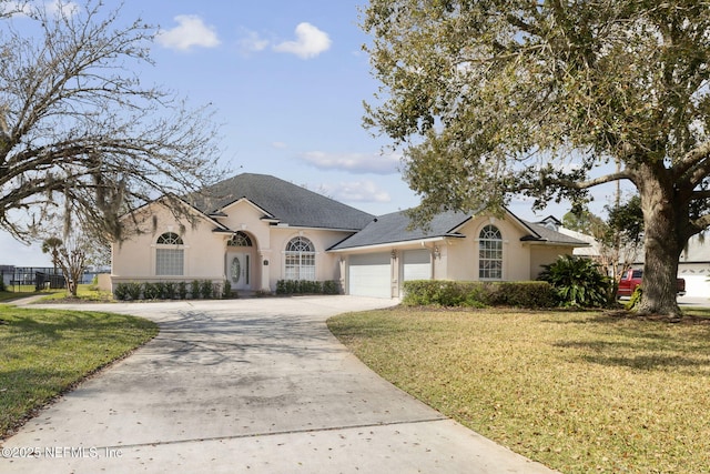 view of front of property featuring driveway, a front lawn, an attached garage, and stucco siding