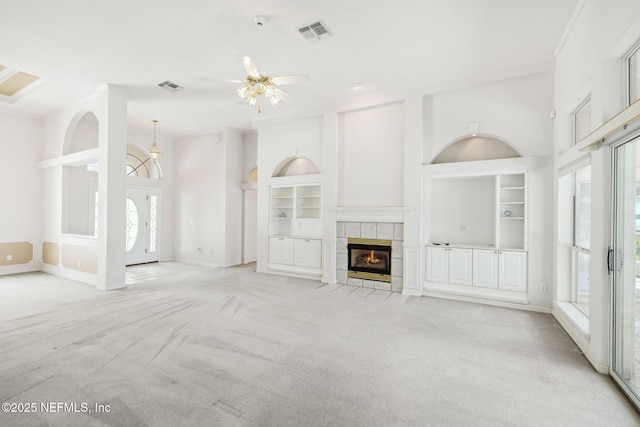 unfurnished living room featuring built in shelves, light colored carpet, visible vents, and ornamental molding