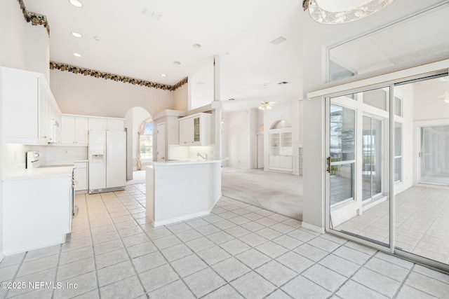 kitchen featuring arched walkways, white appliances, light tile patterned floors, and white cabinetry