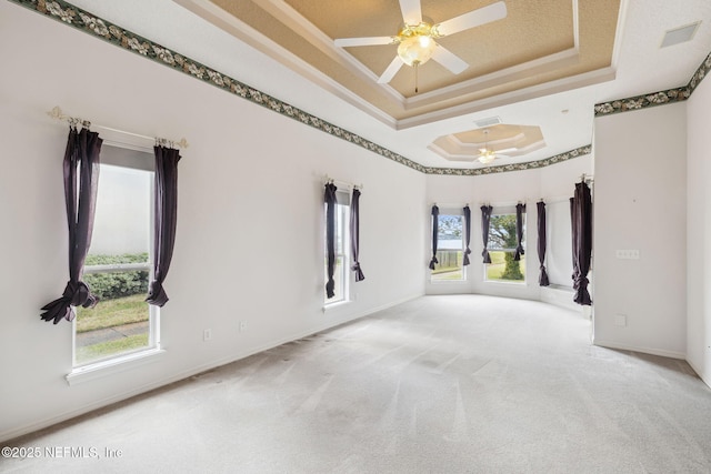 carpeted empty room featuring a raised ceiling, visible vents, ceiling fan, and baseboards