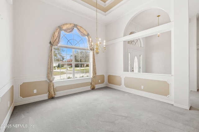 spare room with baseboards, a healthy amount of sunlight, carpet flooring, and a notable chandelier