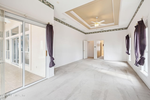 carpeted empty room featuring crown molding, a tray ceiling, and ceiling fan