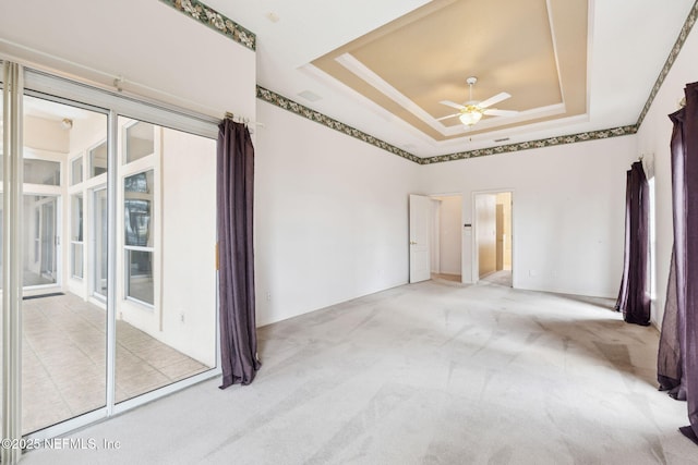 carpeted empty room featuring a tray ceiling and a ceiling fan